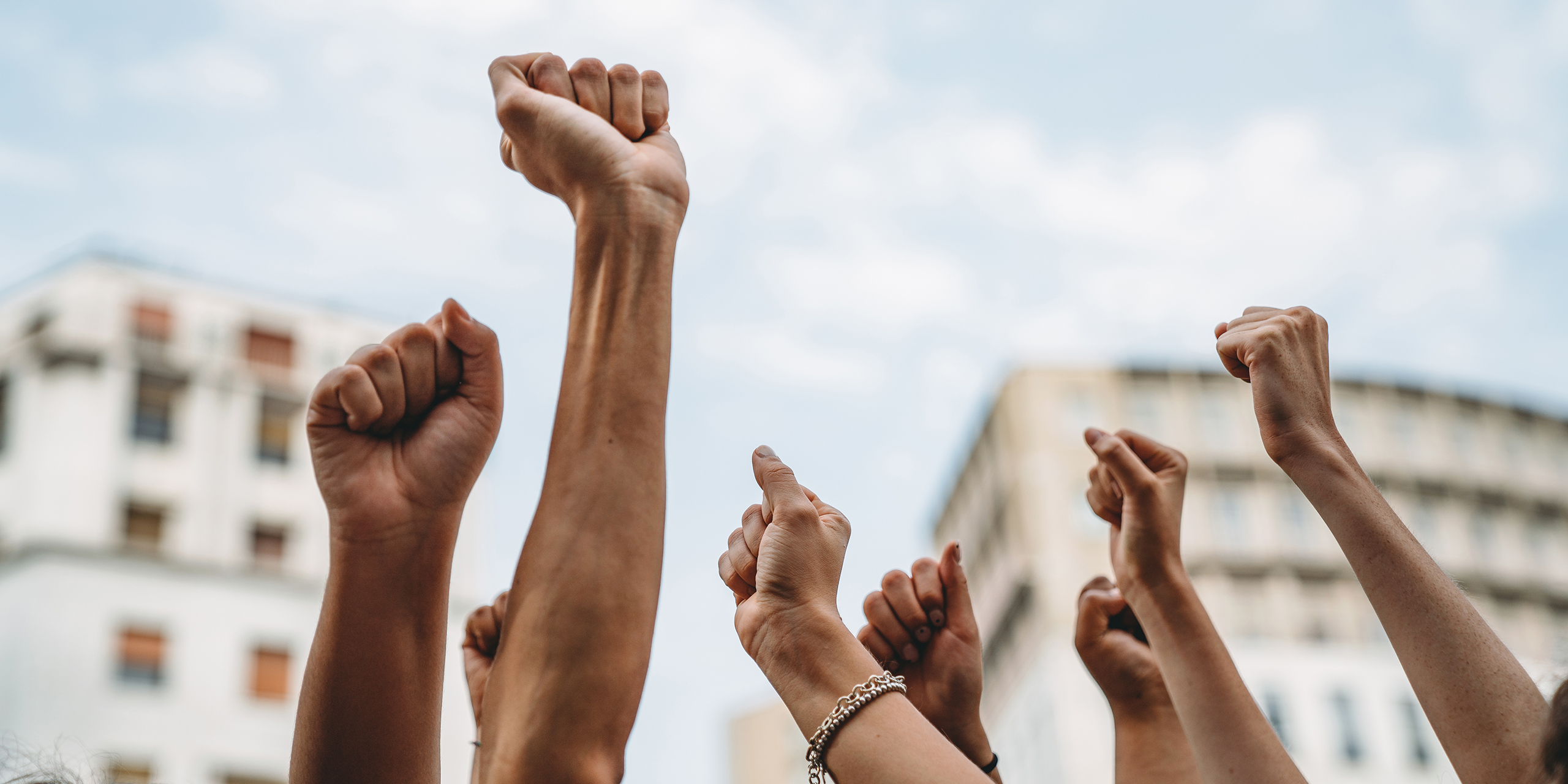 People with raised fists at a demonstration in the city. Multi-ethnic group of people together on strike.