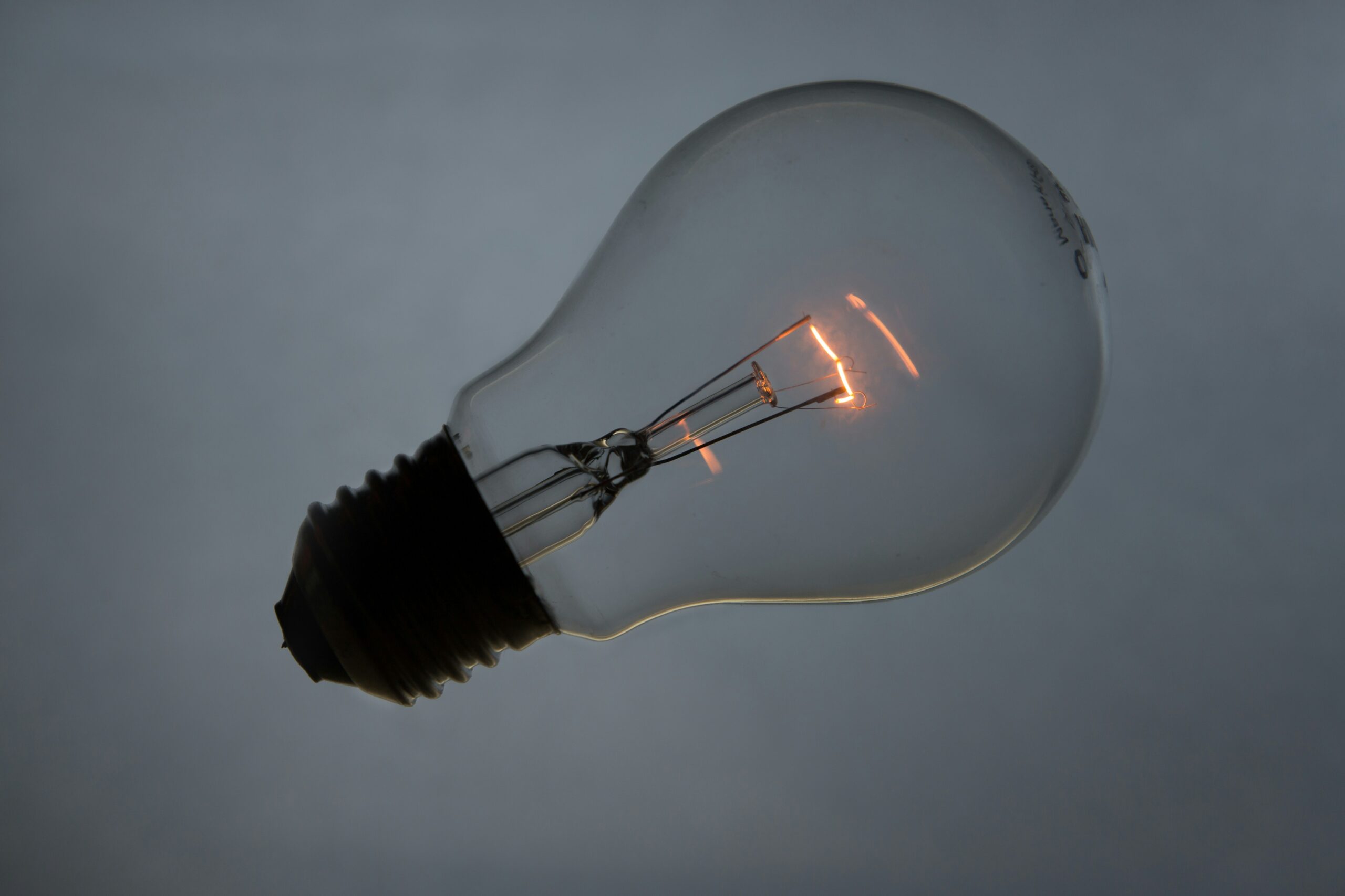 A barely lit light bulb against gray background
